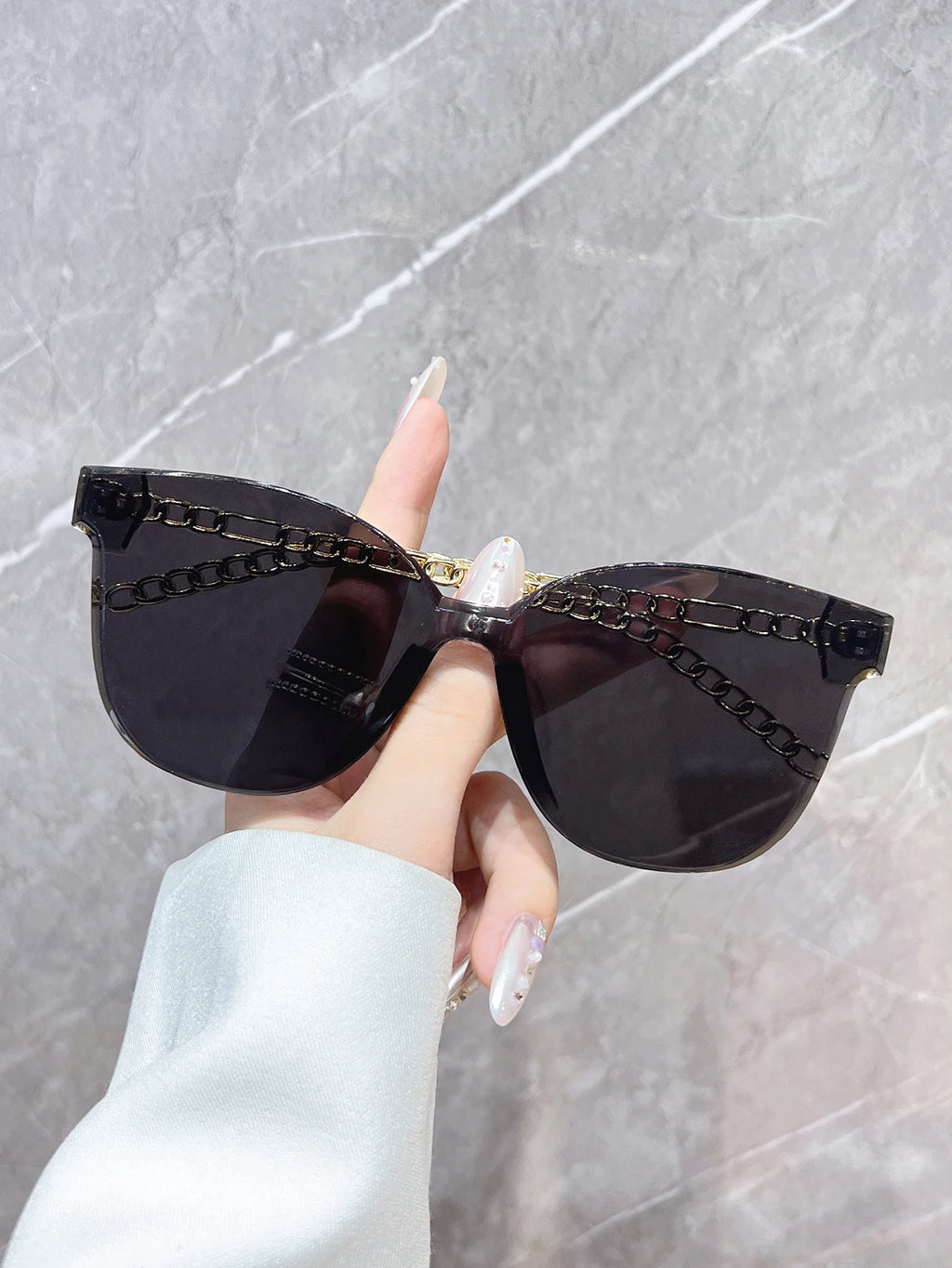 A stylish, frameless, oversized, square-shaped fashion sunglasses with unique chain-style armbands. Perfect for wearing at beach